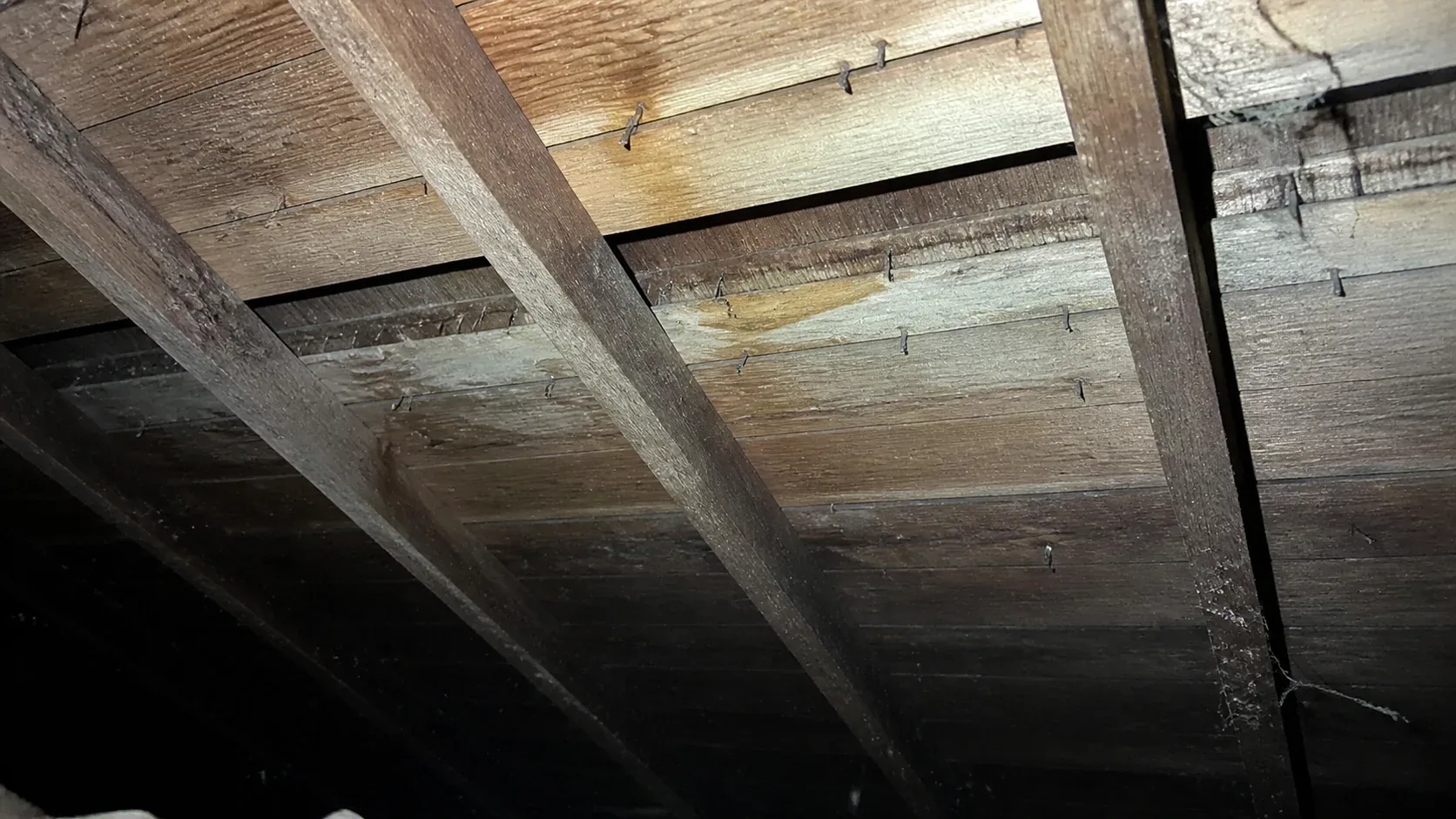 An attic view looking up at wood shake roof sheathing showing evidence of a second layer installed over the original