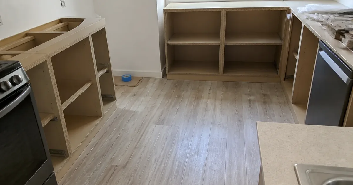 Freshly installed particleboard kitchen cabinetry and new laminate flooring in a recently remodeled Fountain Valley tract home