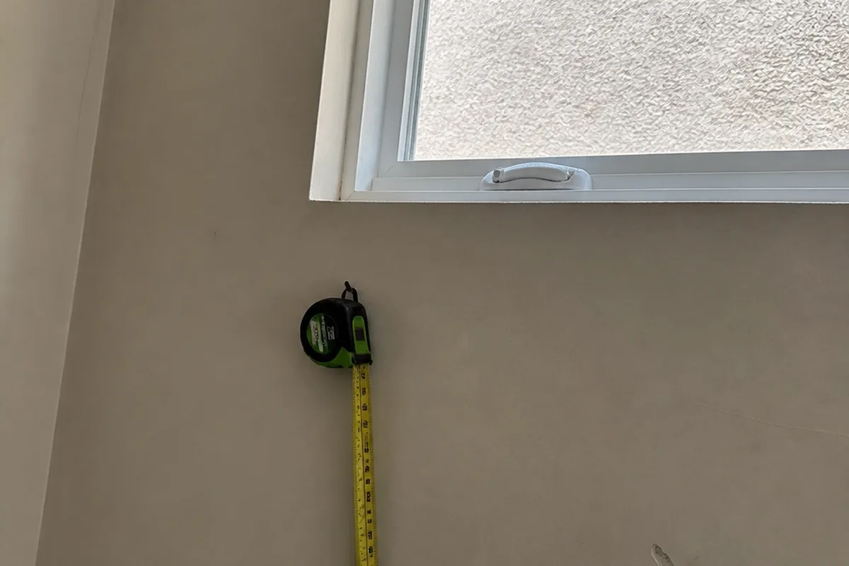 A close view of a small fixed window mounted high on a bedroom wall in a Fremont home, well above the height needed to meet emergency escape and rescue opening requirements