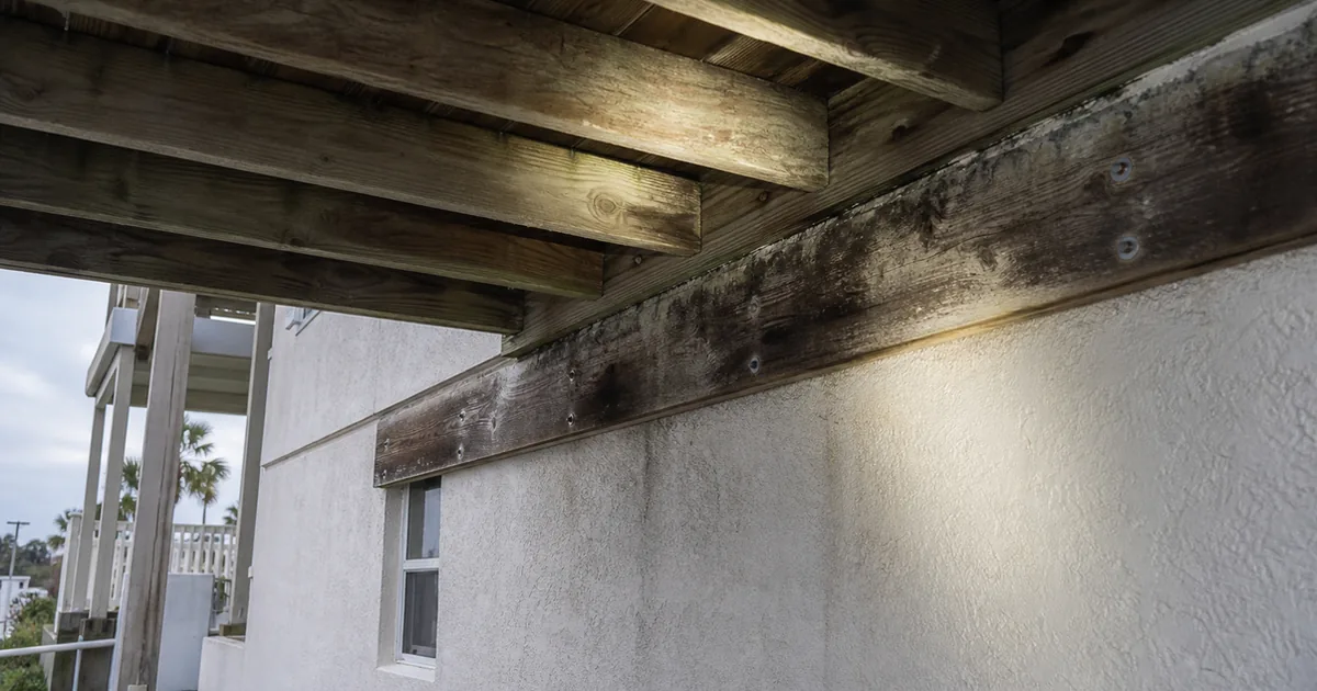 Underside of an elevated wood deck on a multi-level Manhattan Beach home showing the ledger connection and water staining