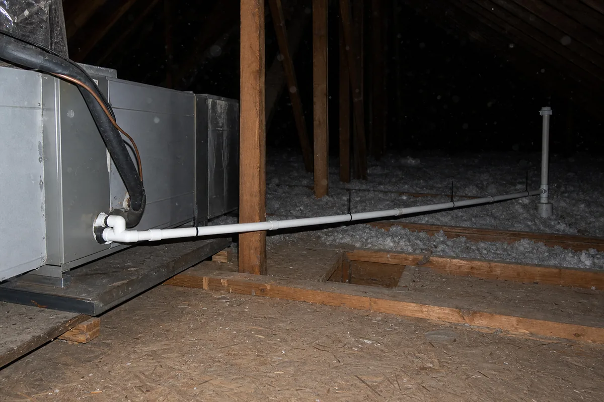 A condensate drain line running from an attic air handler with visible slope and termination, checked for proper pitch and a secondary safety pan