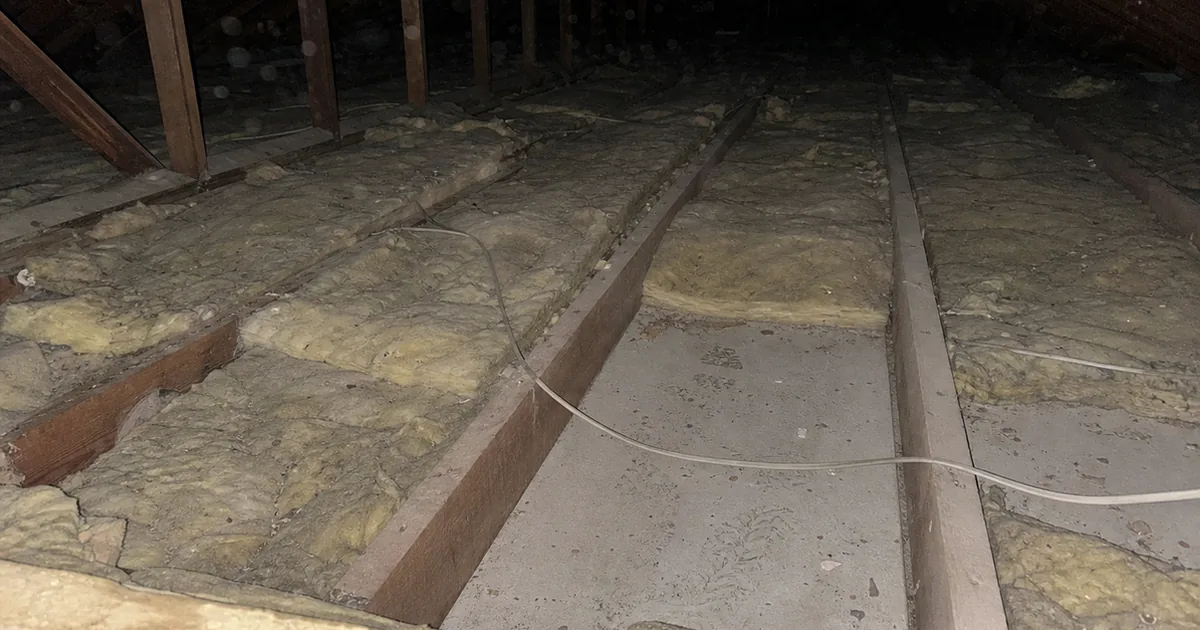 Woodland Hills attic with thin uneven insulation batts and joists showing through, photographed during an inspection