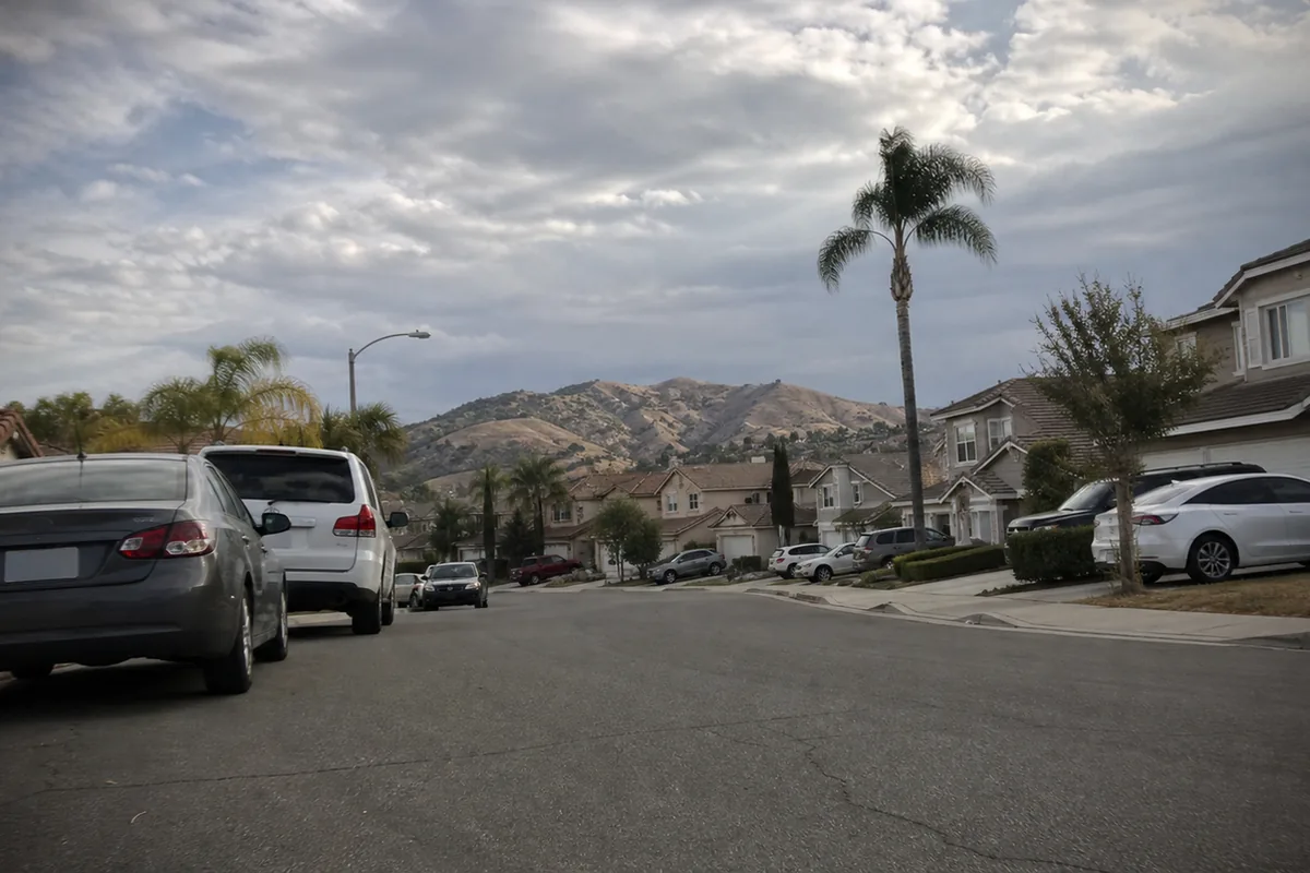 Street-level view of the Tuscany Hills neighborhood in Lake Elsinore, a master-planned community of slab-on-grade single-family homes set against the dry foothills of the Inland Empire