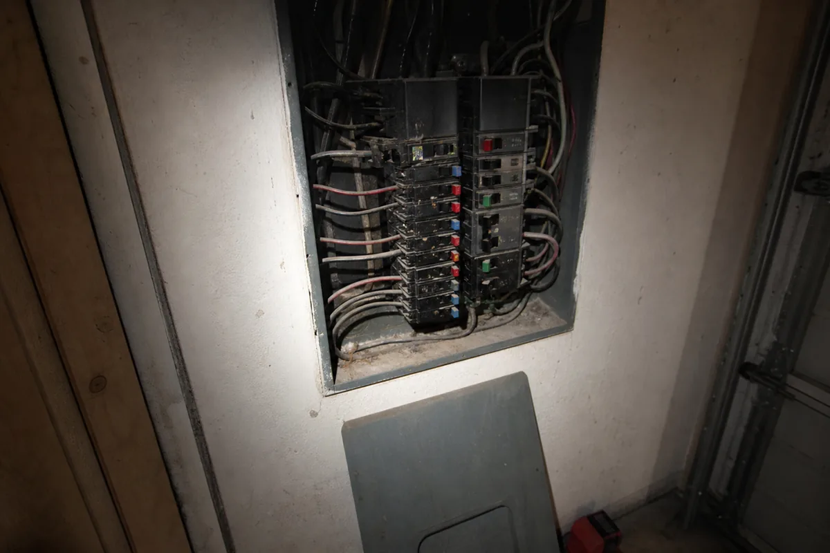 Aged Zinsco electrical panel with dust-covered breakers lit by a flashlight beam in the garage of an older Escondido home, the kind of installation Inspection.re still finds during pre-listing walkthroughs of homes built before 1980